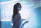 A woman standing in front of a screen with cyber code written on it