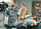 A patient lying on a table surrounded by three medical staff 