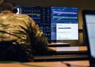 A man in a military uniform working at a computer