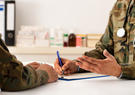 Two military officers chatting and filling out a form