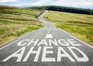 A rural highway with the words "Change Ahead" painted on the road