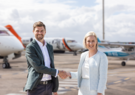 man and woman shaking hands on airport tarmac