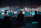 view from behind 3 employees working in a airport tower