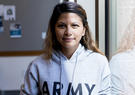 woman standing by window in army hoodie