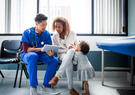 Male doctor showing digital tablet to mother by toddler in hospital