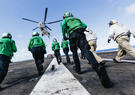 Sailors assigned to supply department runs towards cargo on the flight deck of Nimitz-class aircraft carrier USS George Washington (CVN 73) after it was dropped off by an AS-332 Super Puma helicopter