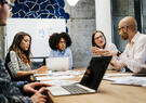 group of 5 people sitting at table collaborating