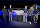 five people stand in front of a boat