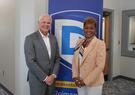Leidos CEO Tom Bell and Drake State President Dr. Patricia Sims pose in front of a Drake State banner.