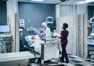 A doctor and nurse assist a patient in a hospital bed.
