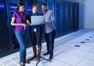 three employees in front of network racks