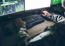 A person in military uniform works on a computer.