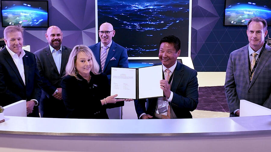 A woman and a man in business attire in the foreground holding up a binder to show the pages. 