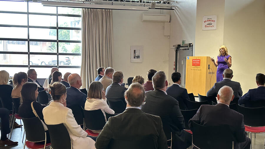 Speaker addresses a seated audience during a professional event in a conference venue.