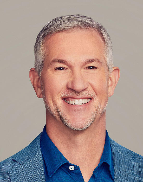 A headshot-style portrait of Jeff McElfresh in a dark blue shirt, open collar, and a blue blazer
