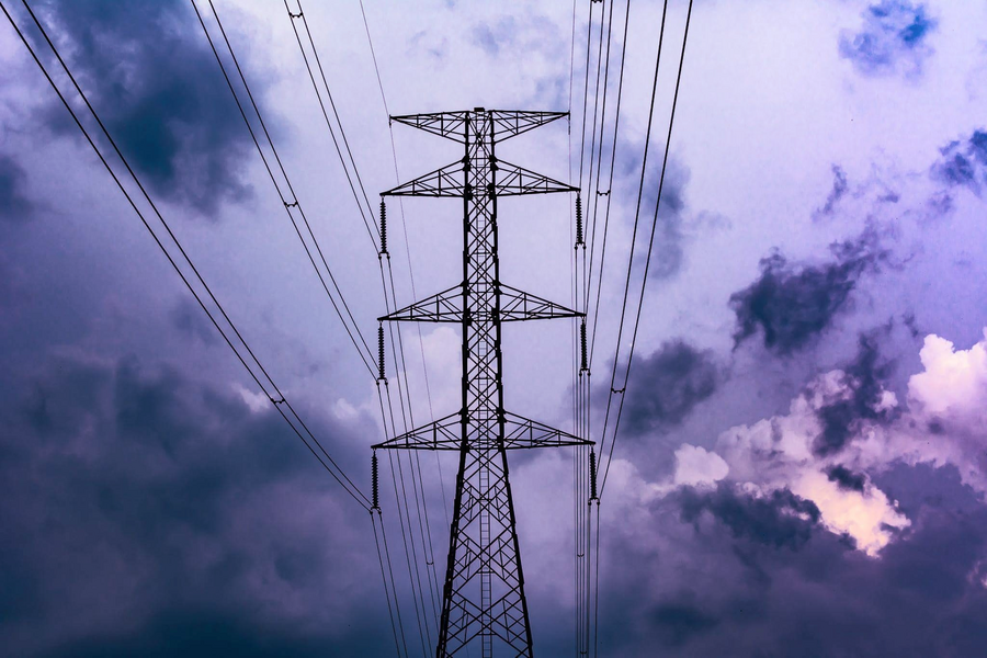 A power line with a cloudy background with a purple hued filter 