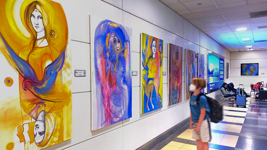 A young traveler takes a moment to appreciate the beauty of a painting hanging in an airport terminal