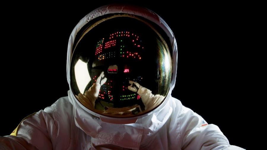 An astronaut in space making adjustments to a control panel