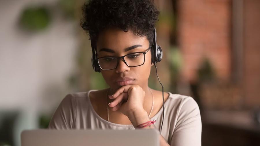 A teenager wearing headphones completing an online course