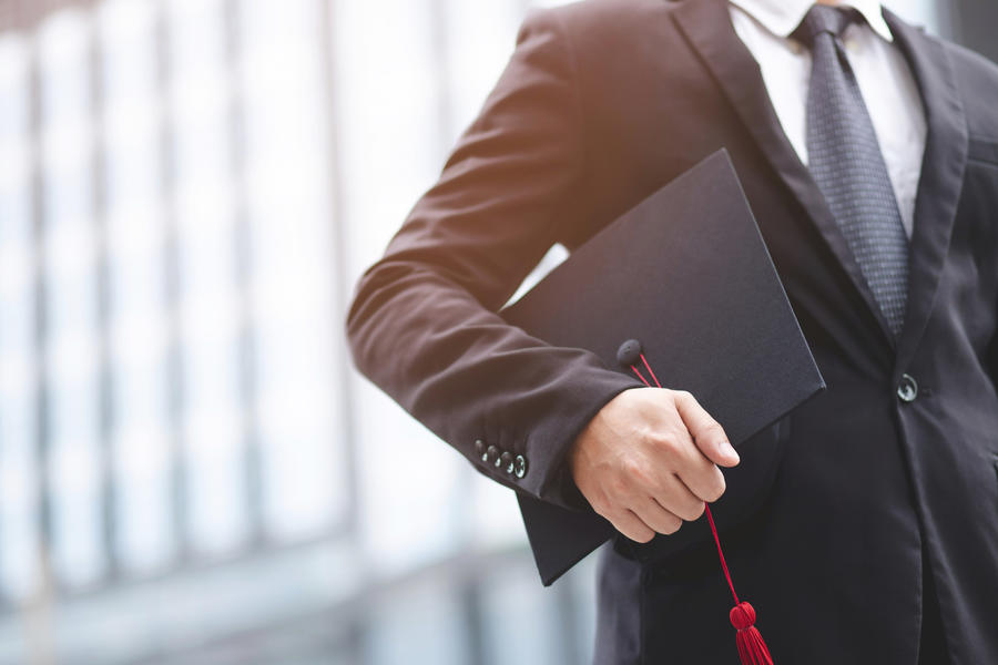 man holding mortarboard by his side