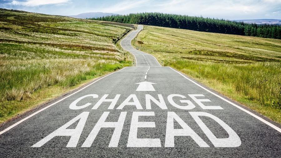 A rural highway with the words "Change Ahead" painted on the road