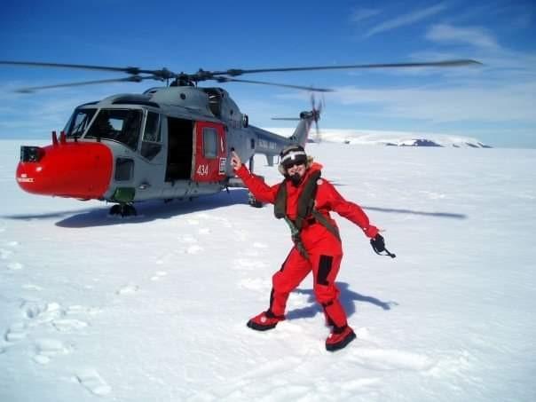 Woman standing on ice next to helicopter