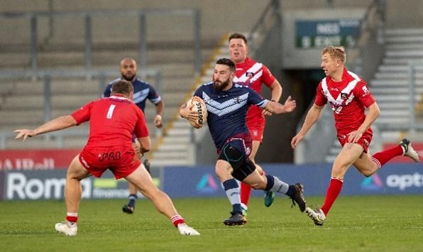 A man running with a rugby ball surrounded by people trying to tackle him