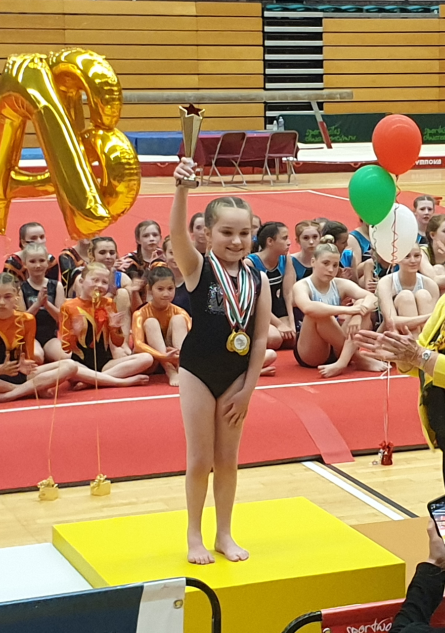 Sara holding trophy at gymnastics tournament