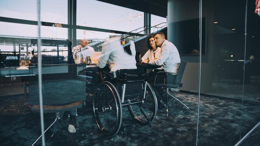 A meeting of colleagues in an office including a women in a wheelchar