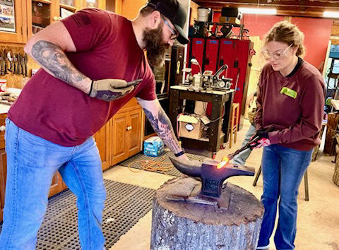 Man and woman blacksmithing