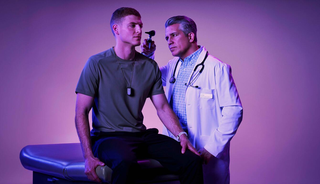 doctor administering a health exam to a young service member on an exam table