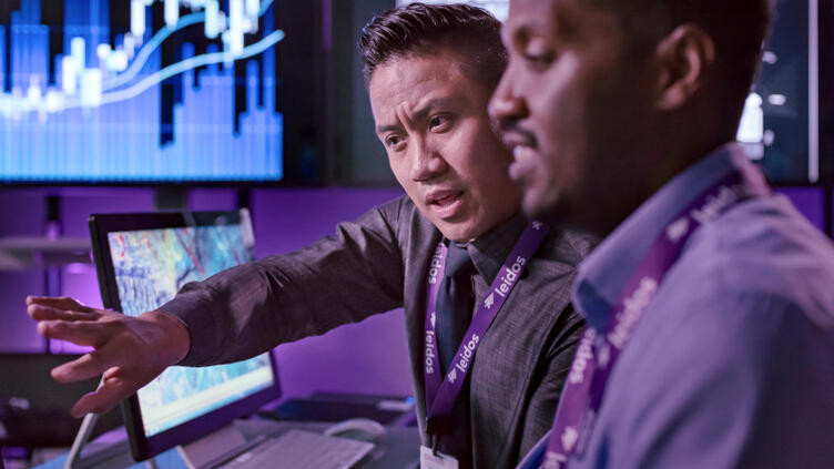 Two men discuss a solution on a computer screen.