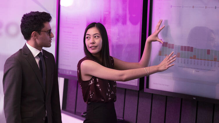 Coworkers looking at large screen with data on it