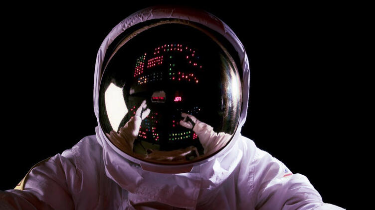 An astronaut in space making adjustments to a control panel