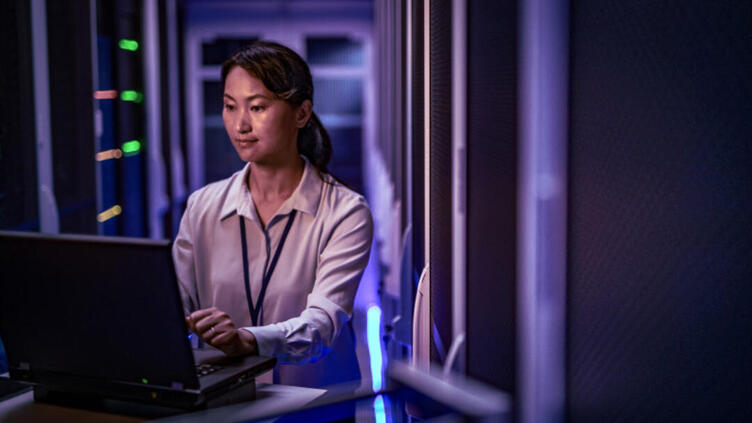A woman works on a laptop in a data center