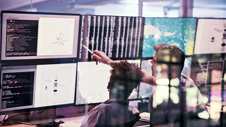 A pair of people look at computer screens