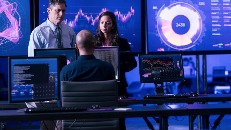 team working with large monitors behind them