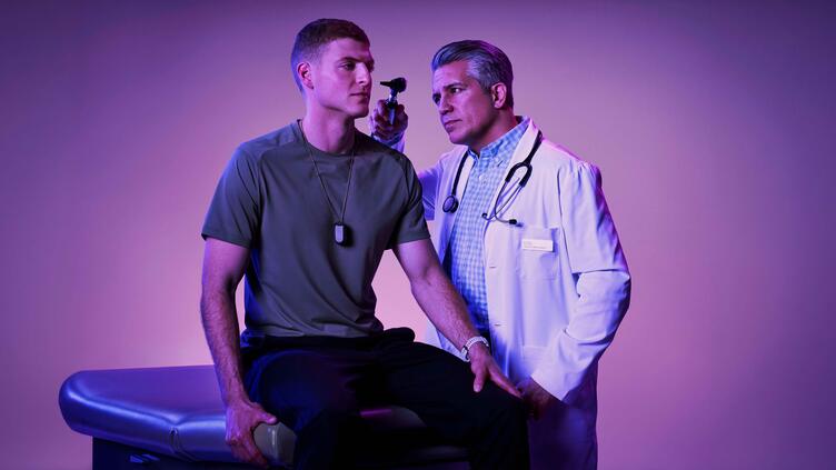 doctor administering a health exam to a young service member on an exam table