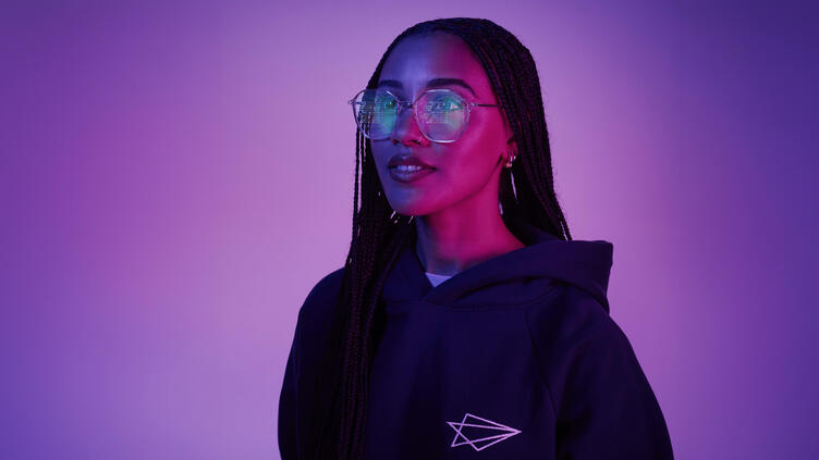 Woman with larger glasses reflection shows computer code on monitor