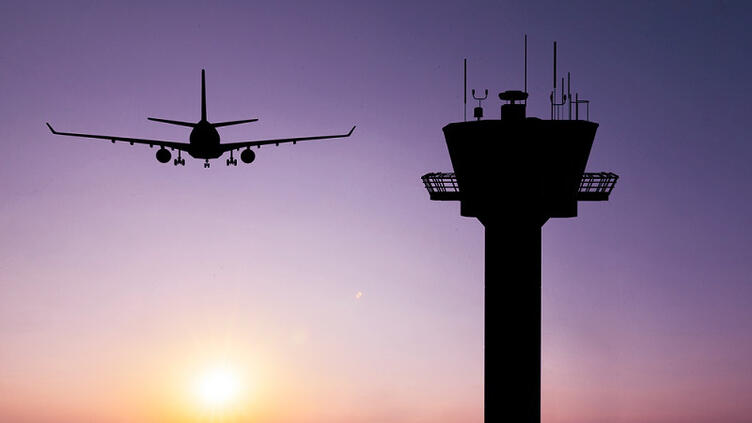 airplane flies by an air traffic control tower