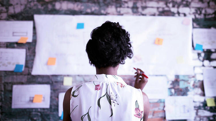 Woman looking at paper and postits on a wall