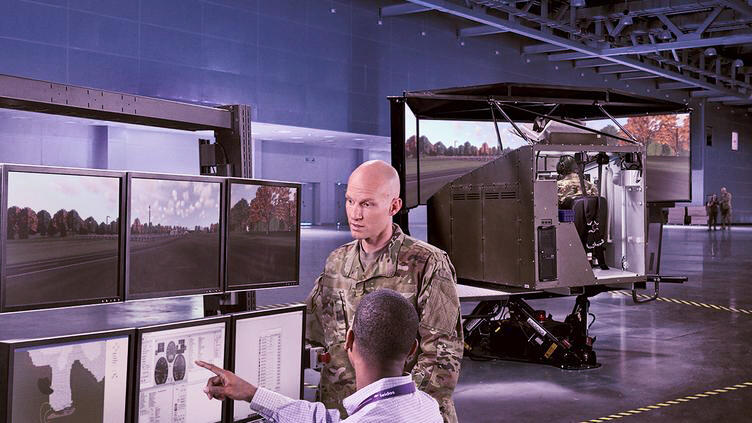A man in a military uniform looks at a screen a man in a collared shirt is pointing at