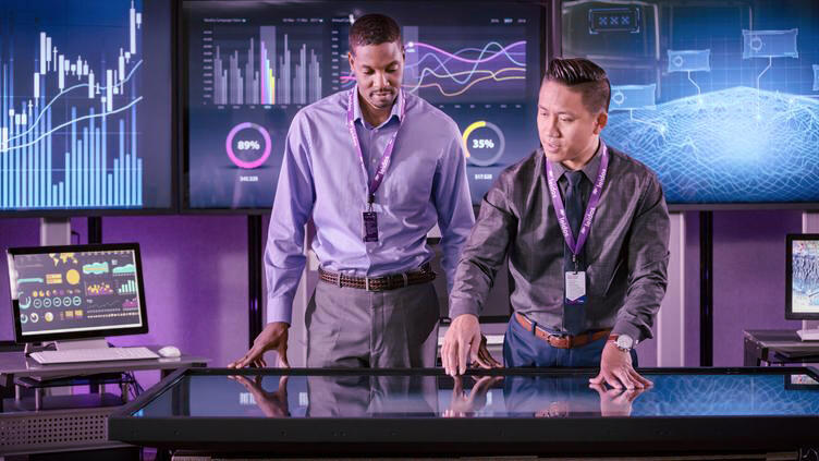 Two men pointing a digital screen 