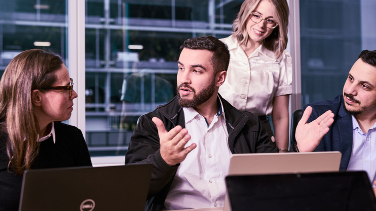 A man sitting down gesturing surrounded by colleagues