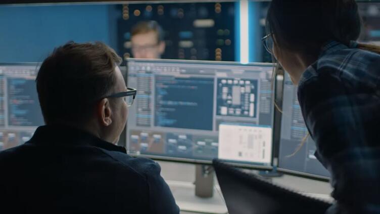 two software developers analyzing their code on a monitor
