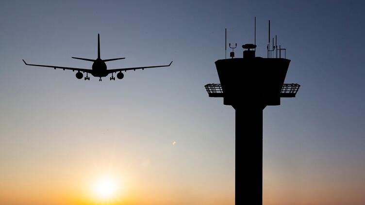 airplane flies by an air traffic control tower