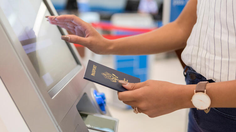 Woman standing at kiosk holding passport