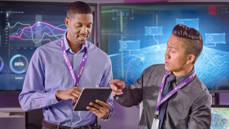 2 men looking at tablet screens in background