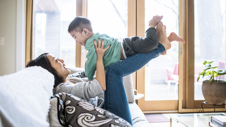 Woman playing with child on a sofa at home