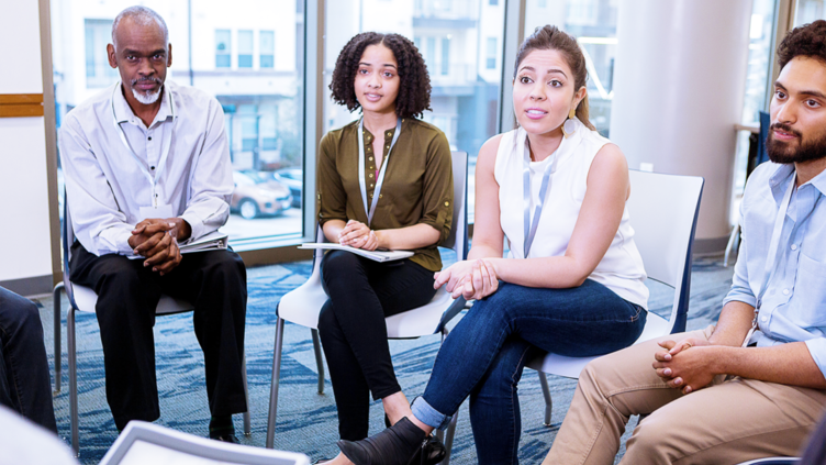 Small group of men and women in discussion during therapy session